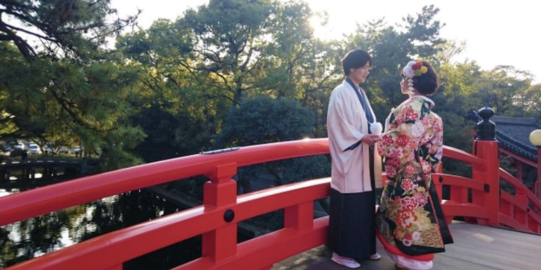 朱色の橋の上で見つめ合う和装姿の新郎新婦