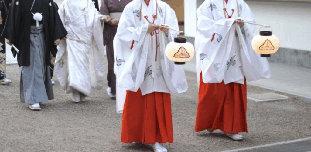 和装の一行が神社の境内を歩く結婚式の行列
